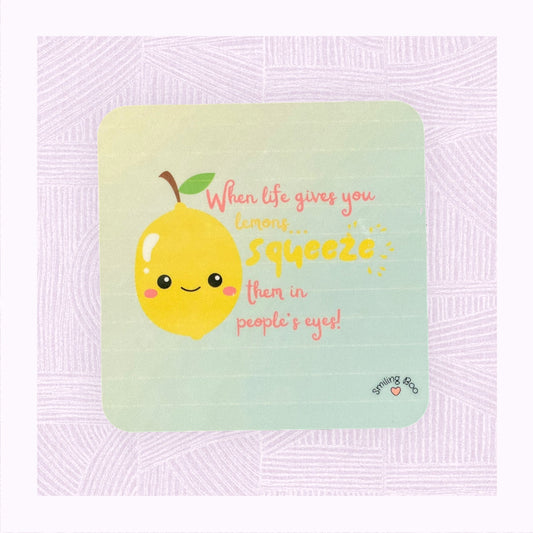 Square coaster with a blue into yellow faded background, a cute lemon character in the foreground with the phrase ‘When life gives you lemons, squeeze them in people’s eyes’.