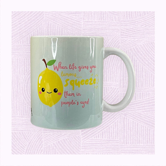 Ceramic mug with a blue into yellow faded background, a cute lemon character in the foreground with the phrase ‘When life gives you lemons, squeeze them in people’s eyes’.