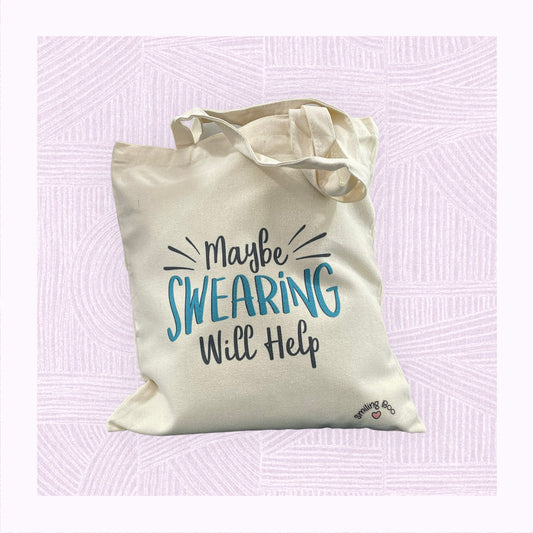Canvas tote bag with he phrase ‘Maybe swearing will help’ on it as if exploding off the bag.