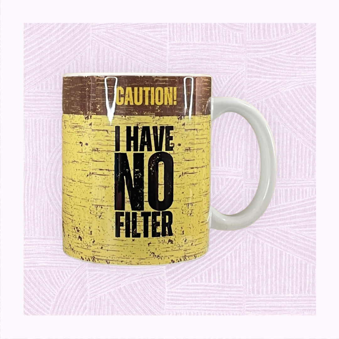 Ceramic mug with a yellow and black distressed background, with the phrase ‘Caution! I Have No Filter’.