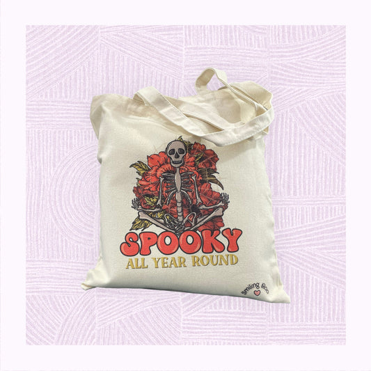Canvas tote bag with a large skeleton in the foreground with the phrase ‘Spooky All Year Round’ underneath it.