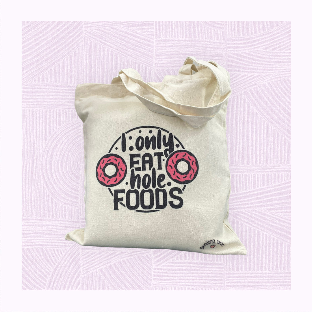 Canvas tote bag with the phrase ‘I only eat hole foods’ with a pink doughnut either side.