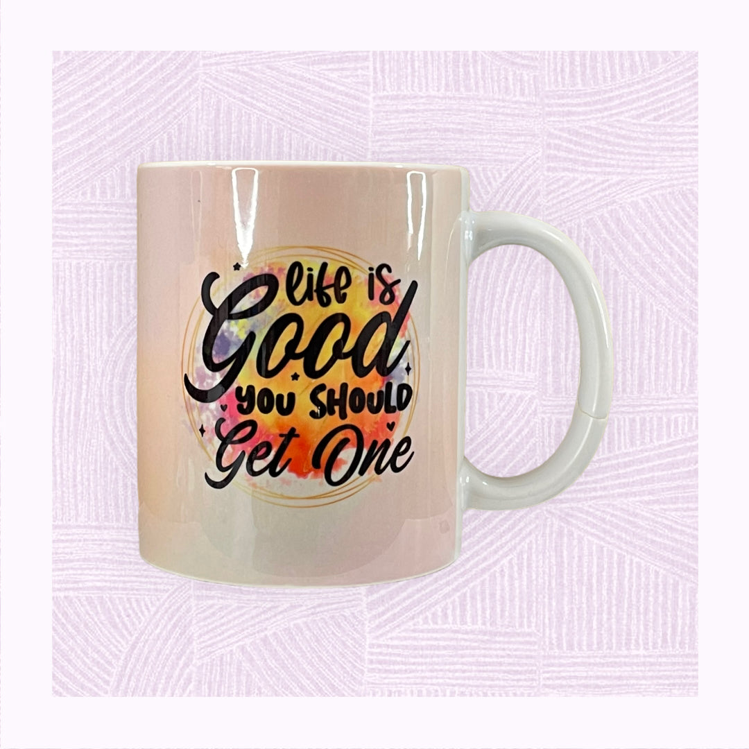 Ceramic mug with printed pastel background, and a colourful watercolour patch with the phrase ‘Life is Good. You should get one’.