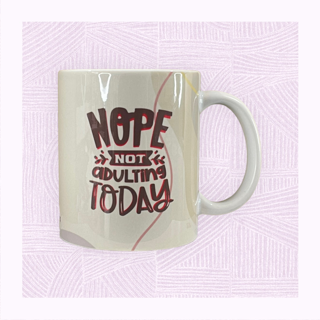 Ceramic mug with a pastel background and the phrase ‘Nope! Not Adulting Today’.