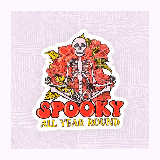 Die cut sticker with a large skeleton in the foreground with the phrase ‘Spooky All Year Round’ underneath it.