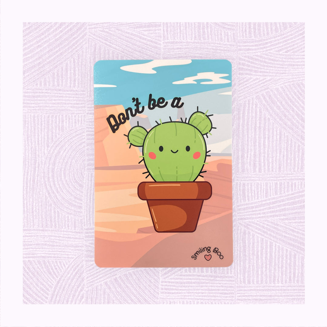 Postcard art print with printed desert background, a cute cactus character with the phrase ‘Don’t be a…’ above it.